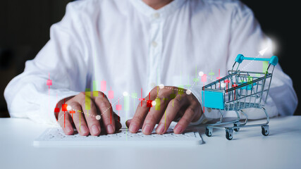 Business man analyzing marketing graph with technology, shopping cart and keyboard on white table.