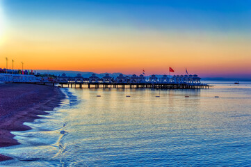 Empty beach with sun beds and sun shades during early summer morning