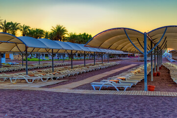 Empty beach with sun beds and sun shades during early summer morning