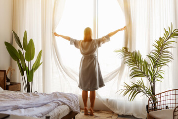 Woman wake up with a fresh and open the curtains on the windows. - obrazy, fototapety, plakaty