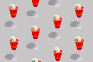 Creative pattern made of Halloween spooky red cocktails with bloody eyes on grey background. Festive drink. Halloween party composition in a minimalist style.