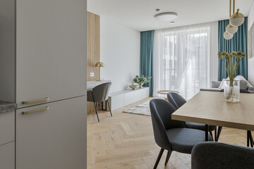 Modern minimalist kitchen and dining room interior design  with wooden furniture, oak floor. blue chairs.  Aesthetic simple interior design concept.