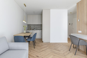 Naklejka na ściany i meble Modern minimalist kitchen and dining room interior design with wooden furniture, oak floor. blue chairs. Aesthetic simple interior design concept.
