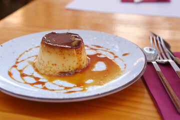  spanish flun pudding dessert closeup photo with teaspoon and cup of coffee on the background