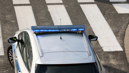 Radiowóz policji zaparkowany przy pasach dla pieszych nadzoruje ruch drogowy.  - obrazy, fototapety, plakaty