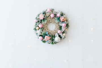 Christmas wreath with pink balls and flowers on a wooden board. Preparation for the holiday.