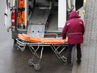A doctor with a stretcher near an ambulance car door. Emergency care for cardiological patients
