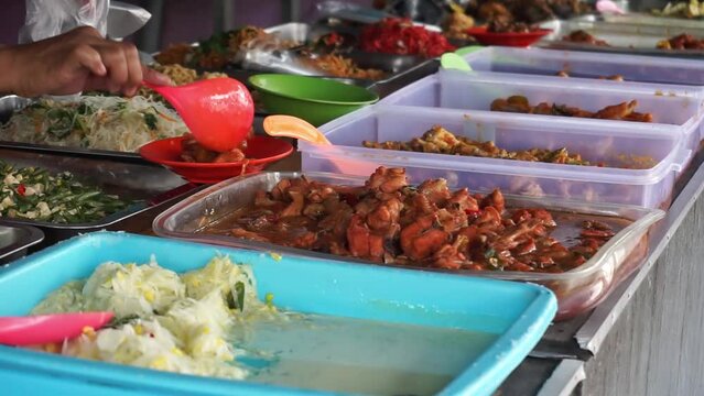 A side dish seller typical of South Kalimantan, Indonesia, is preparing or wrapping several kinds of dishes for buyers.