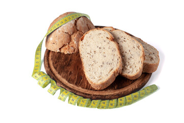 Fresh bread on wooden board with soft tape measure. Tailor's tape and wholegrain bread as concept of diet food. Food restriction concept. Healthy bread.