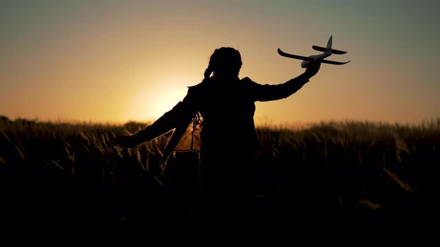 Happy girl with oy in natural park. Child runs on grass with an airplane. Chidhood dream. Happy baby girl with toy airplane at sunset. Child runs on grass in field. Dream travel concept