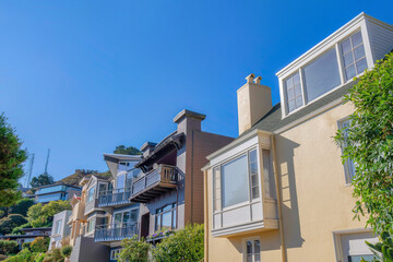 Fototapeta na wymiar Row of suburban houses near a slope with two towers at the back in San Francisco, California