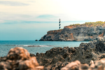 Amanecer en Faro de Portinatx en Ibiza desde las rocas que se adentran en el mar