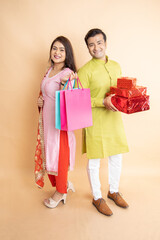 Happy young indian couple holding gift box and shopping bags celebrating diwali festival together...