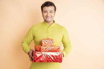 Happy young indian couple holding gift box and shopping bags celebrating diwali festival together...