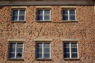 Pattern of a red brick wall structure as background, old house facade with simple windows. Old town...