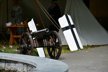 A close up on an old medieval cannon replica standing in the middle of a public park next to a...