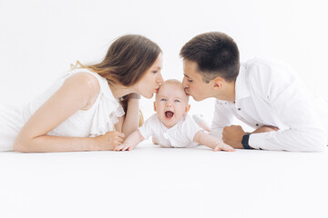 Happy parents lie and kiss their laughing son.