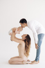 Young happy parents play with their baby and kiss his.