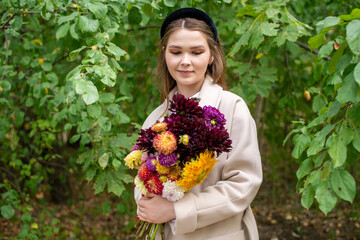 A cute girl with a black headband and long hair holds a bouquet of autumn flowers