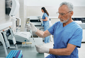 Laboratory technicians working in medical laboratory and researching on blood samples using modern...