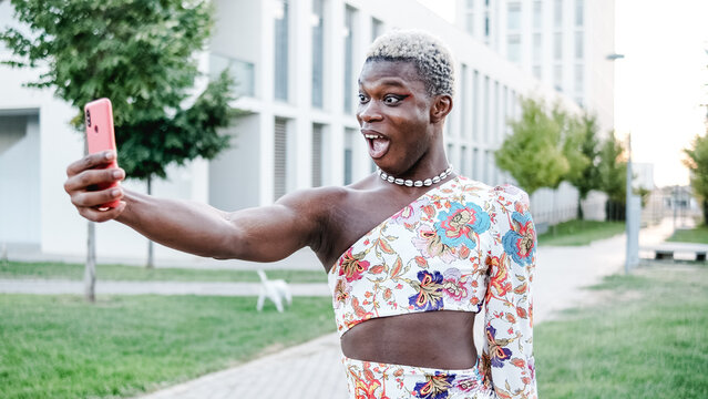 Black Non-binary and young person is taking a selfie outdoor