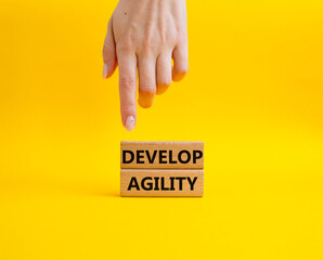 Develop agility symbol. Concept word Develop agility on wooden blocks. Beautiful yellow background....