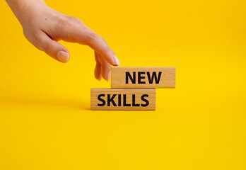 New skills symbol. Wooden blocks with words New skills. Beautiful yellow background. Businessman hand. Business and New skills concept. Copy space.