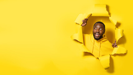 Excited african american man looking at copy space and smiling, showing offer breaking through...