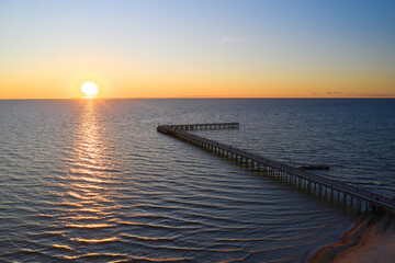 Sunset in the sea. The sun sets beautifully over the horizon against the background of clouds and a pier