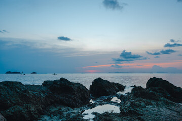 Silhouettes of people riding sup boards in the sea at sunset
