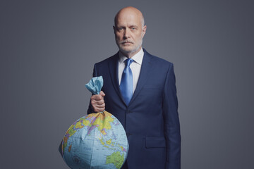 Businessman holding a polluted earth shaped as trash bag