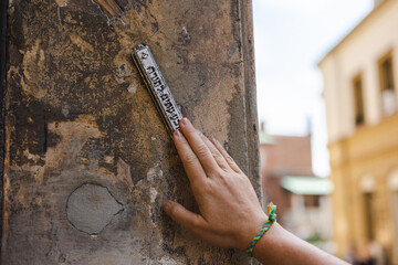 Hand touching mezuzah at the entrance to the house
