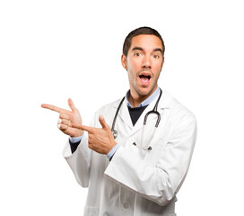 Happy doctor pointing against white background