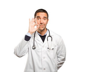 Fototapeta premium Serious doctor with silence gesture against white background