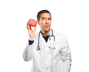 Thoughtful doctor holding a toy brain against white background
