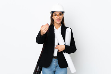 Young architect caucasian woman with helmet and holding blueprints over isolated background inviting to come