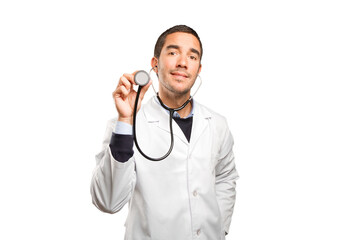 Confident doctor using a stethoscope against white background