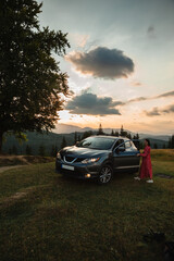 Woman goes to the car. Sunset in the mountains