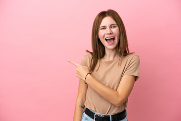 Young English woman isolated on pink background surprised and pointing side