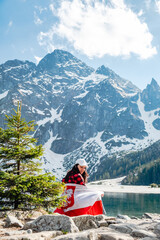 A woman is sitting on the shore of a lake. Morskie Oko, Tatras mountains.