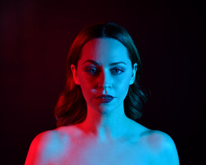 
Close up portrait of beautiful woman model, with pink and blue neon lighting in studio with dark background.