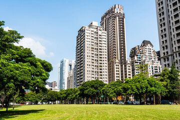 Obraz premium Low angle view of park green space and modern buildings on both sides in downtown Taichung, Taiwan. here is near the National Taichung Theater.
