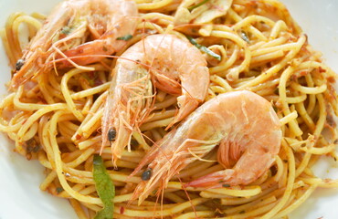 spicy stir fried spaghetti shrimp with chili and basil leaf in tom yum sauce on plate eat couple fresh vegetable salad