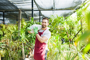 Attractive strong gardener looking happy to work at the nursery garden