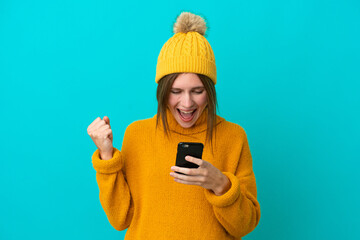 Young English woman wearing winter jacket isolated on blue background surprised and sending a message