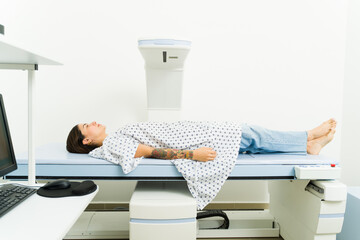 Ill young woman lying on the x-ray machine for densitometry test scan
