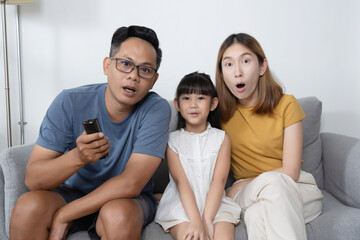 Portrait of Asian family watching excited movie on sofa in living room