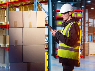 Warehouse manager. Man with tablet in front of boxes. Guy in warehouse worker uniform. Career in...