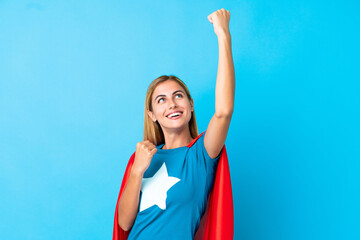 Blonde woman over isolated background in superhero costume and celebrating a victory