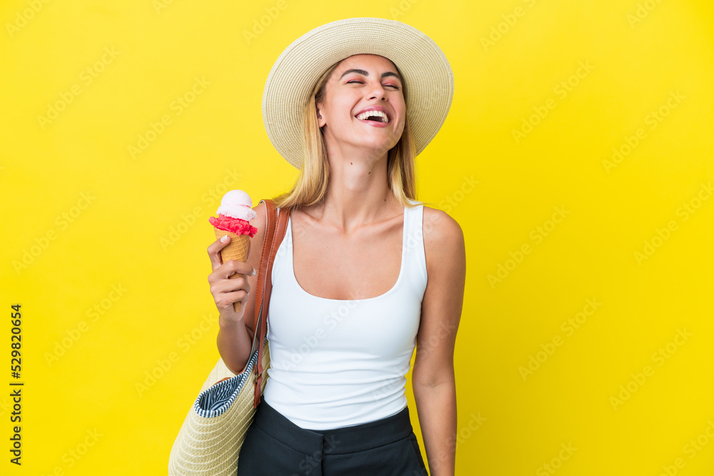 Wall mural Blonde Uruguayan girl in summertime holding ice cream isolated on yellow background laughing - Wall murals